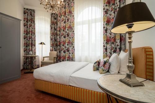 a bedroom with a bed and a table with a lamp at Hotel Villa am Stadthafen in Neustrelitz