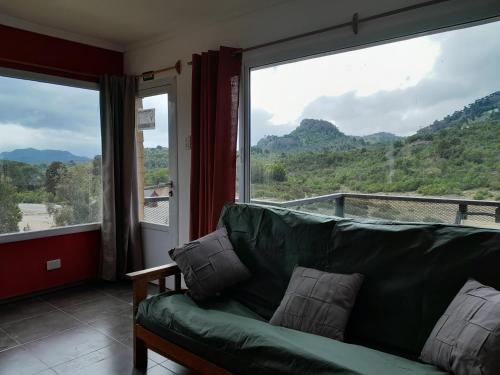 un sofá verde en una habitación con una ventana grande en Apart Hotel Pehuenia en Villa Pehuenia