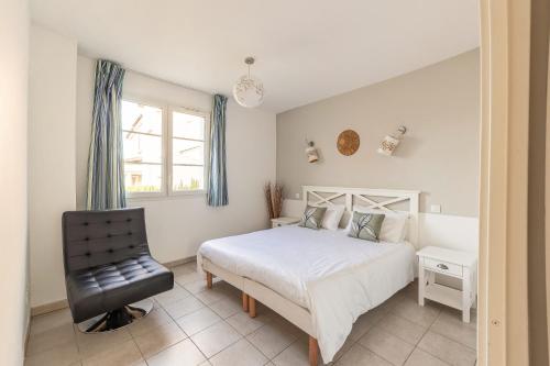 um quarto com uma cama branca e uma cadeira preta em L'Arbois - T2 avec piscine entre Aix et Marseille em Cabriès
