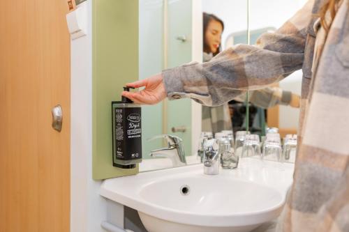 une personne debout devant un lavabo dans une salle de bains dans l'établissement ibis budget Zurich City West, à Zurich