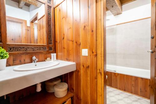 a bathroom with wooden walls and a sink and a tub at Casa Baciver by FeelFree Rentals in Garós