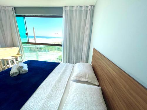 a bedroom with a bed and a large window at Loft Luxo Vista Mar Orla Praia Grande in Arraial do Cabo