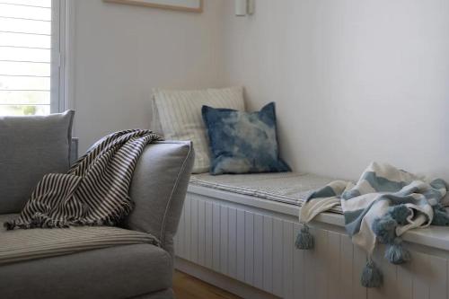 a window seat with a couch and pillows in a room at Sea Notes Yamba in Yamba