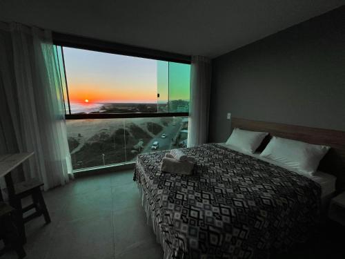 a bedroom with a bed and a large window at Loft Luxo Vista Mar Orla Praia Grande in Arraial do Cabo