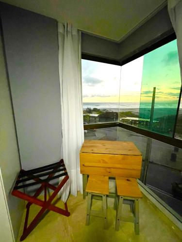 a desk and chair in a room with a large window at Loft Luxo Vista Mar Orla Praia Grande in Arraial do Cabo