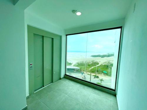 a room with a large window with a view of the ocean at Loft Luxo Vista Mar Orla Praia Grande in Arraial do Cabo