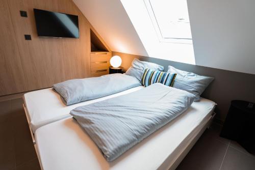 a bedroom with two beds and a tv on the wall at Max Lodging Serviced Apartments in Munich