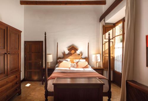 a bedroom with a large bed with a wooden headboard at La Residencia, A Belmond Hotel, Mallorca in Deia