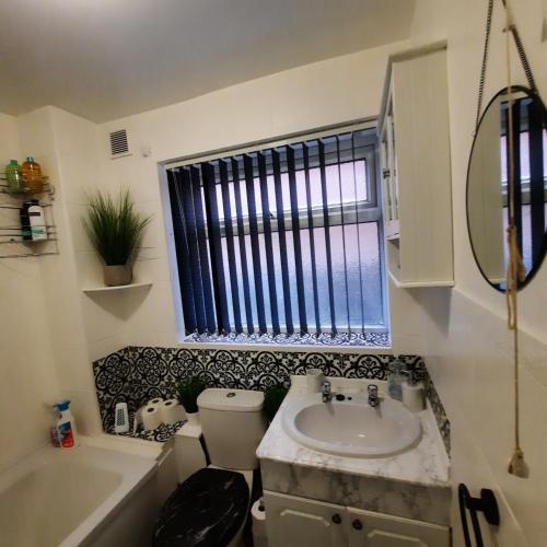 a bathroom with a sink and a toilet and a window at Blenheim Way is a beautiful apartment in a quiet location yet minutes from major attractions and City centre Great for families Sleeps 6 in Birmingham