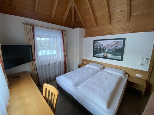 um quarto com uma cama, uma mesa e uma televisão em Residence Palmai em Ortisei