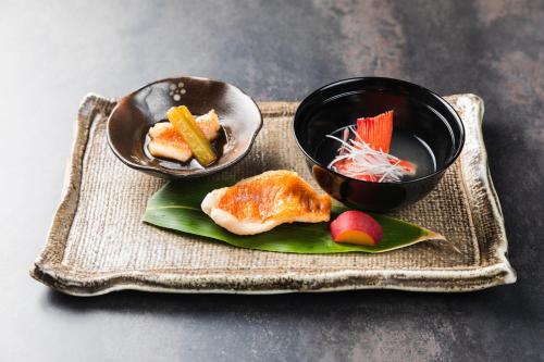 a plate with two bowls of food on a table at Tsuta Onsen Ryokan in Towada