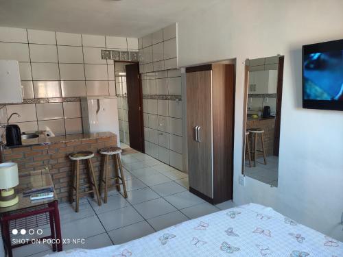 um quarto com uma cozinha com bancos num quarto em Kitnet da Fô em Pelotas