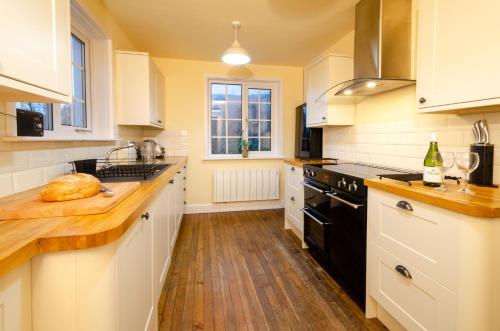 a kitchen with white cabinets and black appliances at Thrang Close, Chapel Stile in Chapel Stile