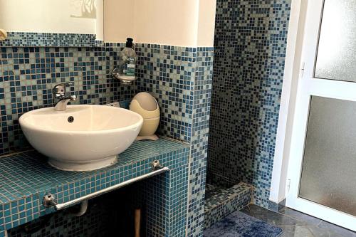 a blue tiled bathroom with a sink and a shower at Villa GÊMEO vue mer, piscine accès privé plage in Calheta Do Maio