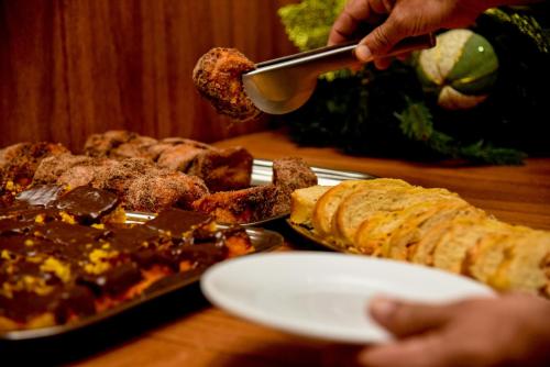 a person holding a spoon over a plate of food at Hotel Titanic Penedo in Penedo