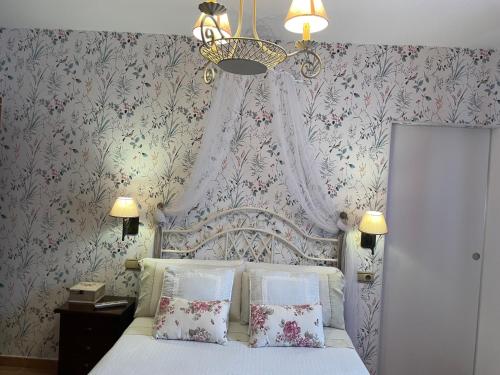 1 dormitorio con cama blanca y papel pintado con motivos florales en Villa Sierra de Gata, en Santibáñez el Alto