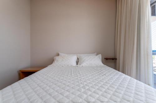a white bed in a room with a window at Cobertura de alto padrão com vista para a Praia do Forte in Cabo Frio