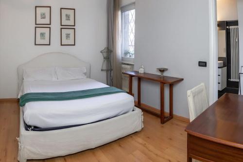 1 dormitorio con cama, escritorio y mesa en [TridentHome] 5 min from station & free Wifi, en Trento