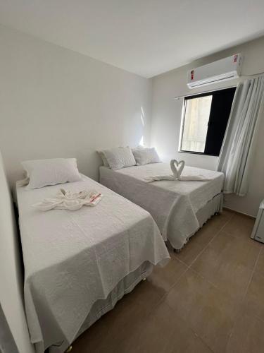 two beds in a white room with a window at POUSADA CASA DA CLAUDIA MARAGOGI in Maragogi