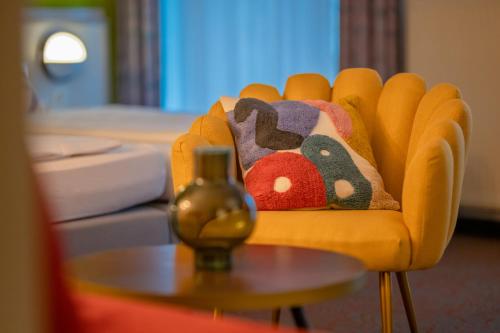 a yellow chair with a stuffed animal pillow on it at Hessenland Hotel Kassel Innenstadt by Stay Awesome in Kassel