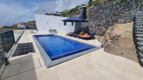 una piscina al lado de un edificio en Majestic Seaview Villa, en Fajã da Ovelha