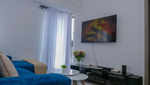 sala de estar con sofá azul y TV en L&M, en Nairobi