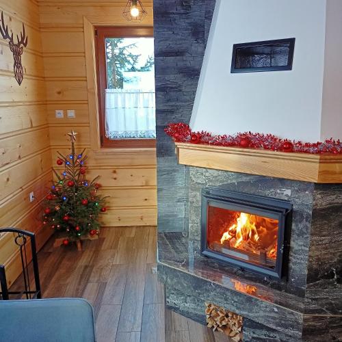 a fireplace and a christmas tree in a room at Domek u Stolarza in Grywałd