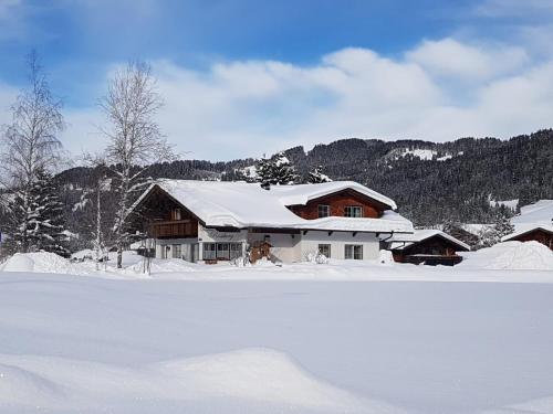 une maison recouverte de neige devant dans l'établissement Landhaus Rossberg, à Tannheim