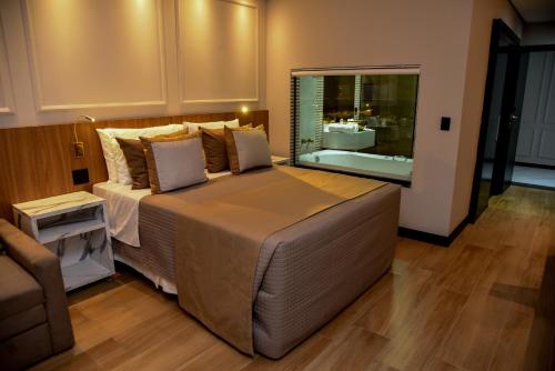 a bedroom with a large bed with a large window at Hotel Titanic Penedo in Penedo