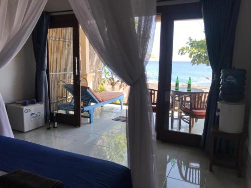 a bedroom with a view of the ocean from a balcony at Tambun Sari Beach Homestay in Amed