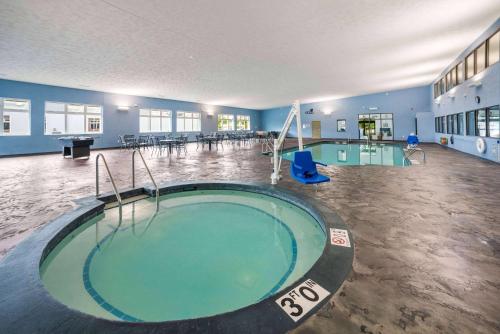 a large swimming pool in a large room with tables at AmericInn by Wyndham Green Bay Near Stadium in Green Bay