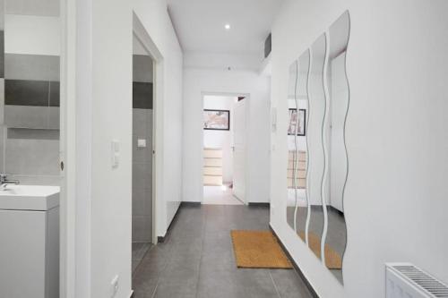 a bathroom with white walls and a hallway with a sink at Sunny&Bright Premium Apartment near New York Café in Budapest