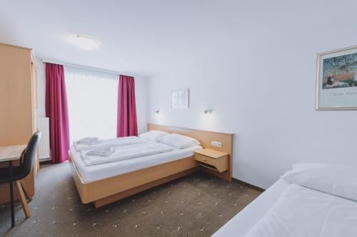 a bedroom with a bed and a desk and a window at Appartements Sulzer by we rent, SUMMERCARD INCLUDED in Zell am See