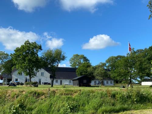 a large white house with a flag on a field at Nyopført luksusværelse i naturskønne og rolige omgivelser in Branderup