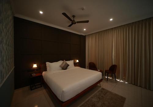 a bedroom with a white bed with a ceiling fan at De Fleur Hotel in Puducherry