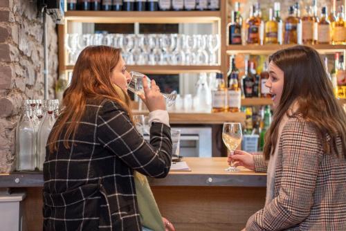 two women standing at a bar drinking wine at The Woodside in Doune