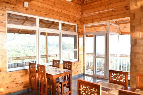 a dining room with a table and chairs and windows at Hotel The Crown in Dharamshala