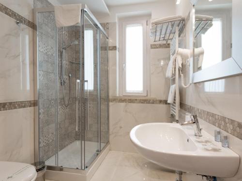 a white bathroom with a shower and a sink at Buono Hotel in Naples