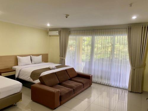 a bedroom with a bed and a couch and a window at Albero Hotel Bogor in Bogor