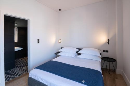 una camera da letto con letto, lenzuola e cuscini bianchi di City's Best-Kept Secret, Eclectic & Luxe Getaway a Kalamáta