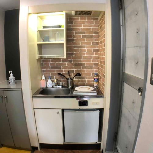 a small kitchen with a sink and a brick wall at Guesthouse Matsu 別館 in Osaka