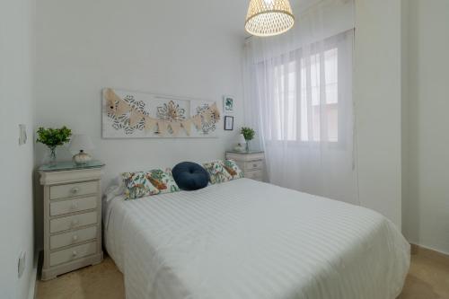 a white bedroom with a white bed and a window at Apartamento Céntrico Isaura in Córdoba