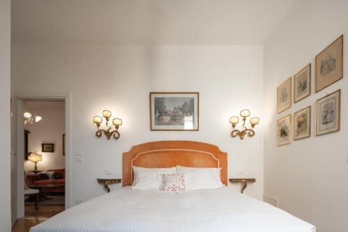 Un dormitorio con una cama blanca con cabecero de madera. en Tiepolo Apartment in the Biennale District R&R, en Venecia