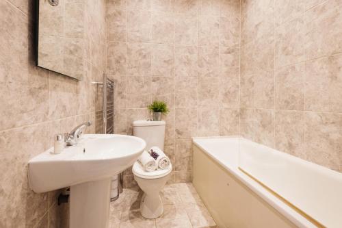 uma casa de banho com um lavatório, um WC e uma banheira em Dream South Kensington Apartment em Londres