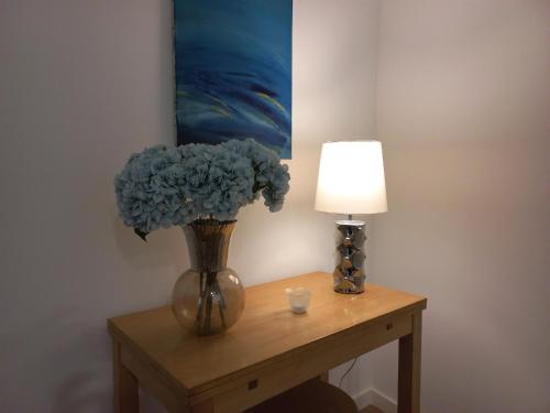un vase avec des fleurs bleues sur une table à côté d'une lampe dans l'établissement Ares do Mar - 4 beds apartment and car parking, à Matosinhos