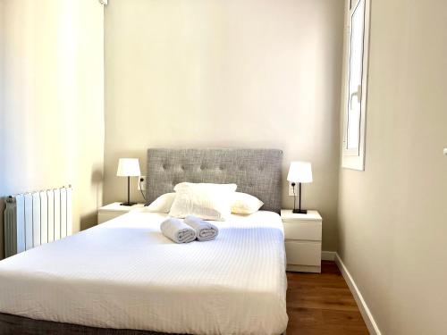 sypialnia z białym łóżkiem i 2 ręcznikami w obiekcie Sunny apartment Gracia - Joanic Renovated w Barcelonie