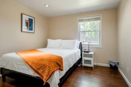 sypialnia z łóżkiem z pomarańczowym kocem i oknem w obiekcie *2bdr Victorian Home away from Home - *Central Loc w mieście Sacramento