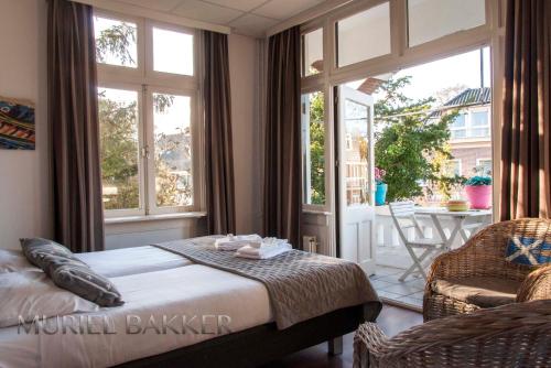 a bedroom with a bed and a chair and windows at Hotel Breeburg in Bergen