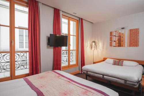 a hotel room with two beds and a window at Hotel Le petit Paris in Paris