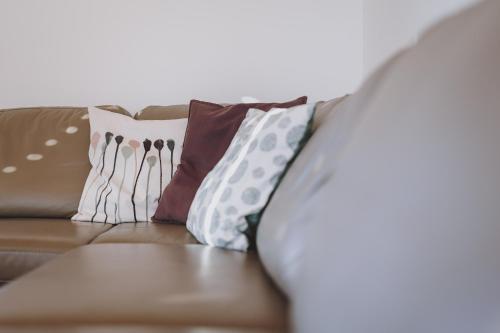 a brown couch with pillows on it at Appartements Sulzer by we rent, SUMMERCARD INCLUDED in Zell am See